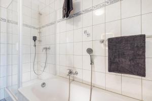 メンディヒにあるVulkan-Suiteの白いタイル張りのバスルーム(シャワー、シンク付)