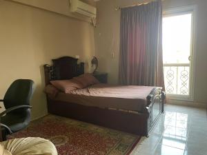 ein Schlafzimmer mit einem Bett, einem Fenster und einem Stuhl in der Unterkunft El Rehab city in New cairo