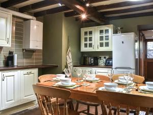 a kitchen with a wooden table with chairs and white cabinets at Stable Cottage in Askrigg