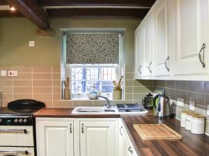 a kitchen with white cabinets and a sink and a window at Stable Cottage in Askrigg +19 photos
