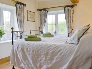 een slaapkamer met een wit bed met groene kussens erop bij The Appleloft in Westleigh