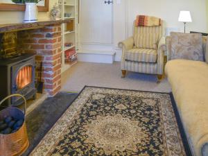 ein Wohnzimmer mit Kamin, Sofa und Sessel in der Unterkunft Gold Cottage in Swaffham
