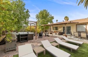 a backyard with white benches and a grill at Stylish home with pool and spa in Las Vegas