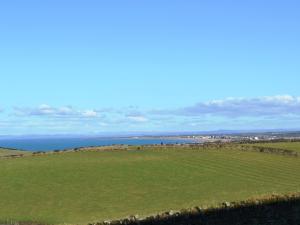 a green field with the ocean in the background at The Old Dairy - Cottage in Crosscanonby