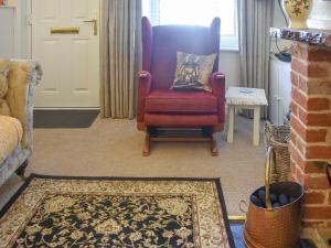 ein Wohnzimmer mit einem roten Stuhl und einem Teppich in der Unterkunft Gold Cottage in Swaffham