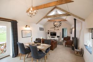 ein Esszimmer mit Tisch und Stühlen und ein Wohnzimmer in der Unterkunft The Blacksmiths - Luxury Cottage Country Views in Ludchurch