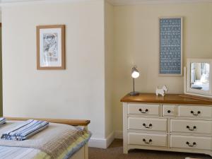 a bedroom with a dresser and a mirror at Grosvenor Cottage in Alnmouth +4 photos