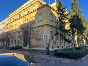 a yellow building with a car parked in front of it at Museum 4 Residence in Debrecen