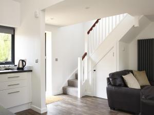 Una sala de estar con un sofá y una escalera. en Ash Barn - Fernhill Farm, en Ryde