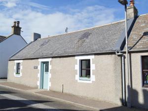 a building with a blue door on a street at Three Creeks Cottage in Portknockie