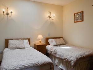 a bedroom with two beds and a lamp on a table at Peace in Whauphill