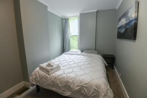 a bedroom with a white bed with a window at Fully Remodeled, Charming Victorian Home in Rochester