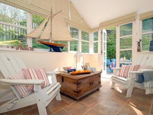 een veranda met twee stoelen en een tafel met daarop een zeilboot bij Haven's Rest in Walton West