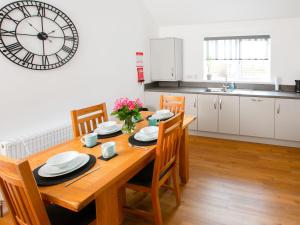 a dining room table with chairs and a clock on the wall at Rossie Cottage in Auchterarder