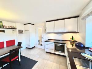 a kitchen with white cabinets and a table and a dining room at Auszeit im Chiemgau in Rottau