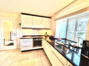 a kitchen with white cabinets and a sink at Auszeit im Chiemgau in Rottau