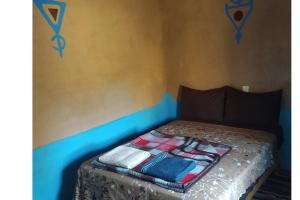 a bed with a blanket on it in a room at Desert house in Merzouga +2 photos