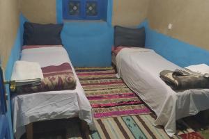 two beds in a room with blue walls at Desert house in Merzouga