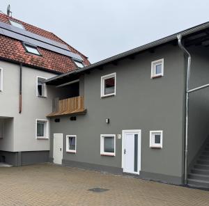 ein graues Haus mit weißen Türen und einer gemauerten Auffahrt in der Unterkunft Ferienwohnung Tee - Time - Lodge und Kirsch - Kiste in Momlingen