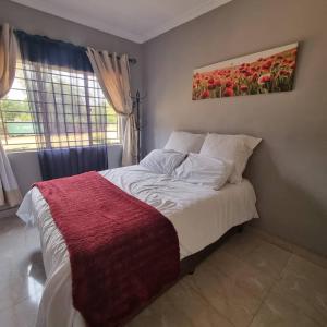 a bedroom with a bed with a red blanket on it at Carl Street Gardens in Kitwe