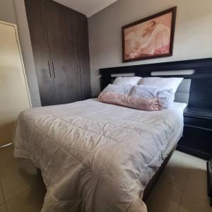 a bedroom with a large bed with a pink comforter at Carl Street Gardens in Kitwe