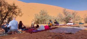 a group of people sitting on the sand in the desert at Desert tours&trips in Zagora +8 photos