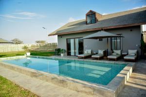einen Pool mit Stühlen und einem Sonnenschirm neben einem Haus in der Unterkunft Bungalow Campo Playa Arena in Chincha