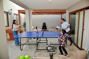 eine Gruppe von Menschen, die um eine Tischtennisplatte stehen in der Unterkunft Bungalow Campo Playa Arena in Chincha