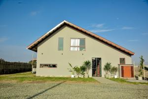 ein weißes Haus mit braunem Dach in der Unterkunft Bungalow Campo Playa Arena in Chincha