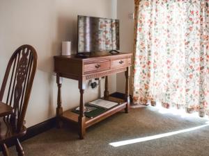 Una mesa de madera con un espejo al lado de una silla. en The Piggy House, en Sheringham