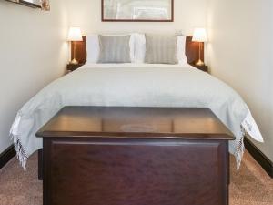 1 dormitorio con 1 cama grande y mesa de madera en The Piggy House, en Sheringham 3 fotos más