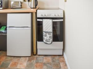 una cocina con estufa y refrigerador en The Piggy House, en Sheringham