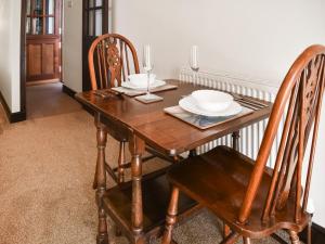 una mesa de madera con sillas y platos. en The Piggy House, en Sheringham