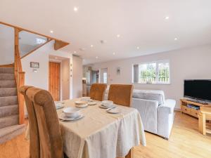 een woonkamer met een tafel, stoelen en een televisie bij Annie's Cottage in Bempton