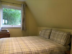 een slaapkamer met een bed met een geruite deken en een raam bij Thistle Lodge - Uk7051 in Glenurguhart