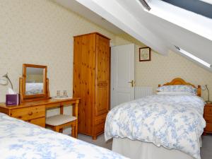 ein Schlafzimmer mit einem Bett, einer Kommode und einem Spiegel in der Unterkunft Molly's Cottage in Glenridding