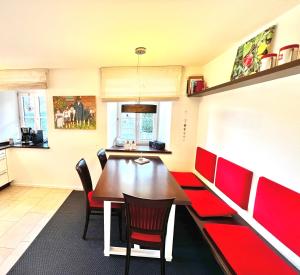 a dining room with a table and red chairs at Auszeit im Chiemgau in Rottau