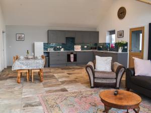 a living room with a couch and chairs and a kitchen at Branwen in Llanfachraeth