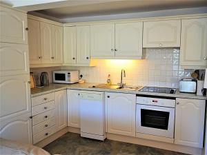 a kitchen with white cabinets and white appliances at Tarquins in Fowey
