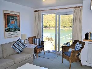 a living room with a couch and chairs and a balcony at Tarquins in Fowey