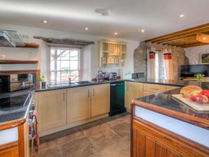 a large kitchen with wooden cabinets and black counter tops at Rhosson Chapel Cottage in St. Davids +19 photos