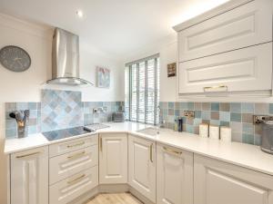 Wainfleet All SaintsにあるThe Cooperage- Uk34818の白いキャビネットと壁掛け時計付きのキッチン