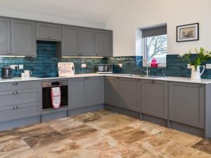 a kitchen with gray cabinets and a sink at Branwen in Llanfachraeth