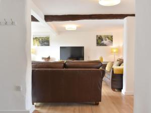 a living room with a brown couch and a tv at Brameley in Cheriton Bishop