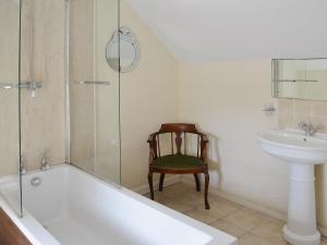 a bathroom with a tub and a sink and a chair at Rockville Cottage - 24376 in Bempton