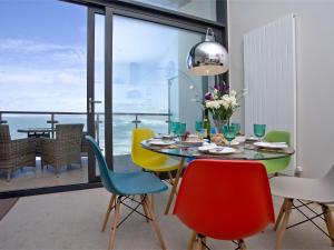 een eetkamer met een tafel en kleurrijke stoelen bij Sunset Bay - 31 Horizon View in Westward Ho