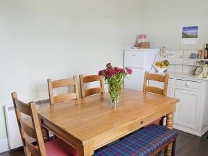 ein Esstisch mit einer Vase mit Blumen darauf in der Unterkunft The Cottage in Garlieston
