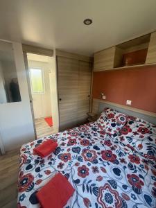 a bedroom with a bed with a red and blue blanket at Bungalow 507 3ch wifi Camping Siblu Lac de Rêves in Lattes