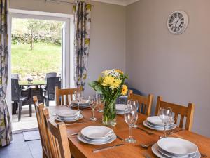 a dining room with a wooden table with a vase of flowers at Bryn Derwen in Llanfair