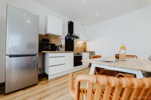 a kitchen with a stainless steel refrigerator and white cabinets at Appartement face aux thermes de vals WIFI-Parking gratuit in Vals-les-Bains
